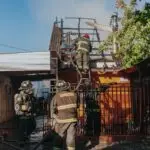 Firefighters working to extinguish a house fire, showcasing bravery and teamwork outdoors.